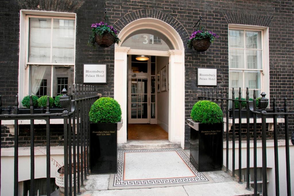 伦敦布卢姆斯伯里皇宫酒店的砖房的前门,有植物