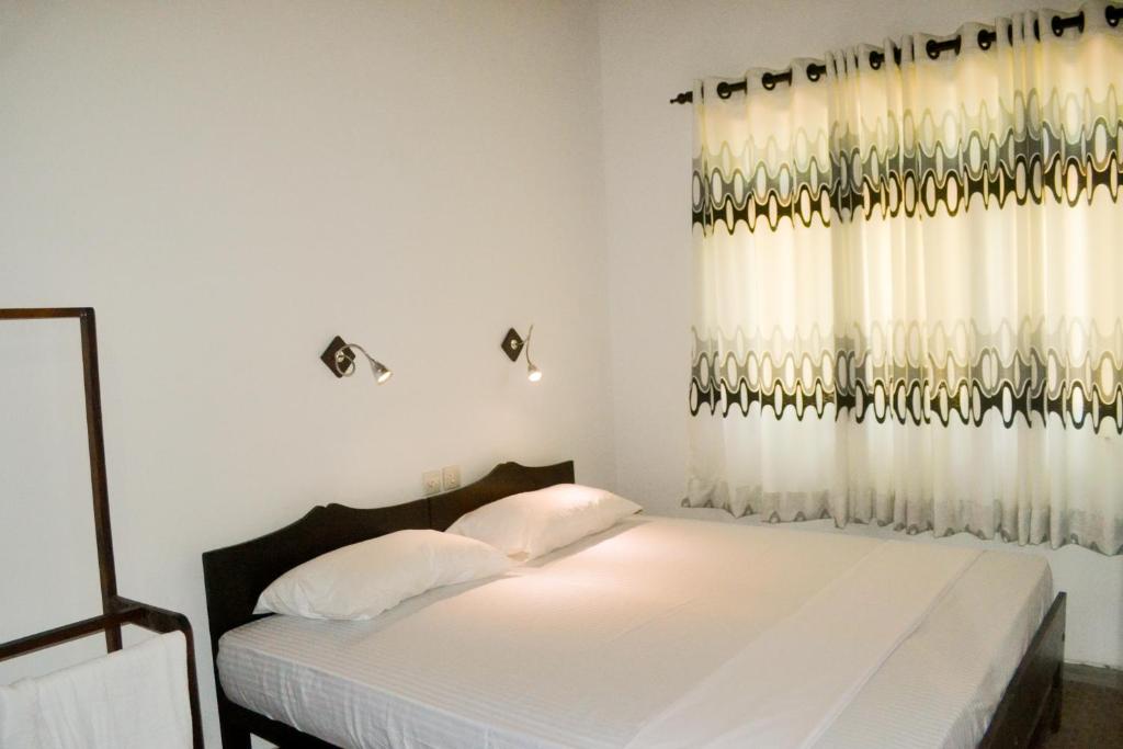 希克杜沃My Place Hikkaduwa的一间卧室配有床和带窗帘的窗户