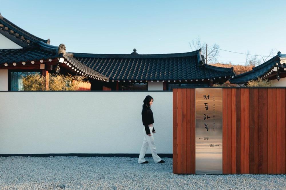 江陵市Gangneung Jeodong Hanok Pension newly built的一名女子在建筑物前行走