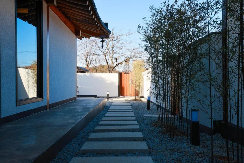 江陵市Gangneung Jeodong Hanok Pension newly built的一条小径,旁边是一座树木繁茂的白色建筑