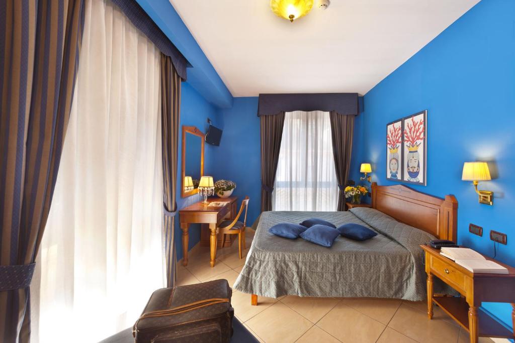 索伦托乌利赛豪华旅馆的一间卧室拥有蓝色的墙壁,配有一张带蓝色枕头的床。