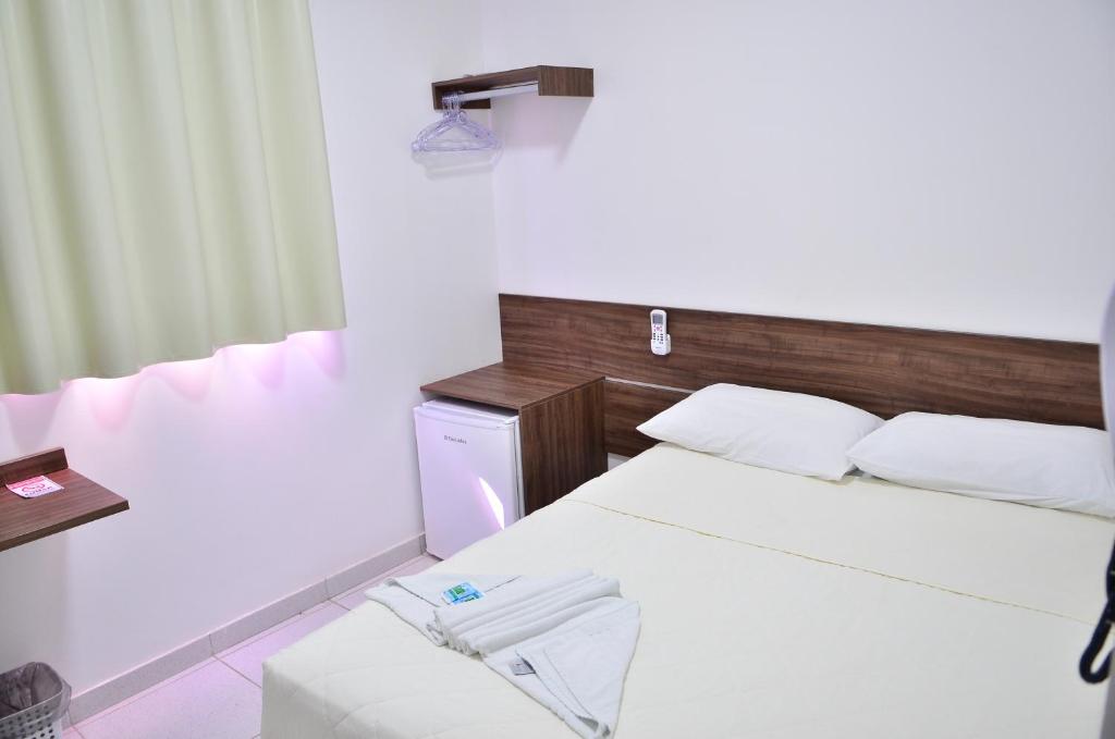 马卡帕诺特酒店的一间卧室配有一张床铺、一张桌子和一台冰箱