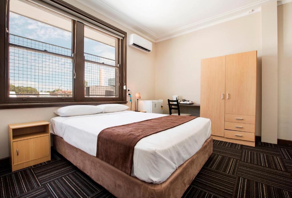 布莱克敦藤伽比酒店的一间卧室设有一张大床和两个窗户。