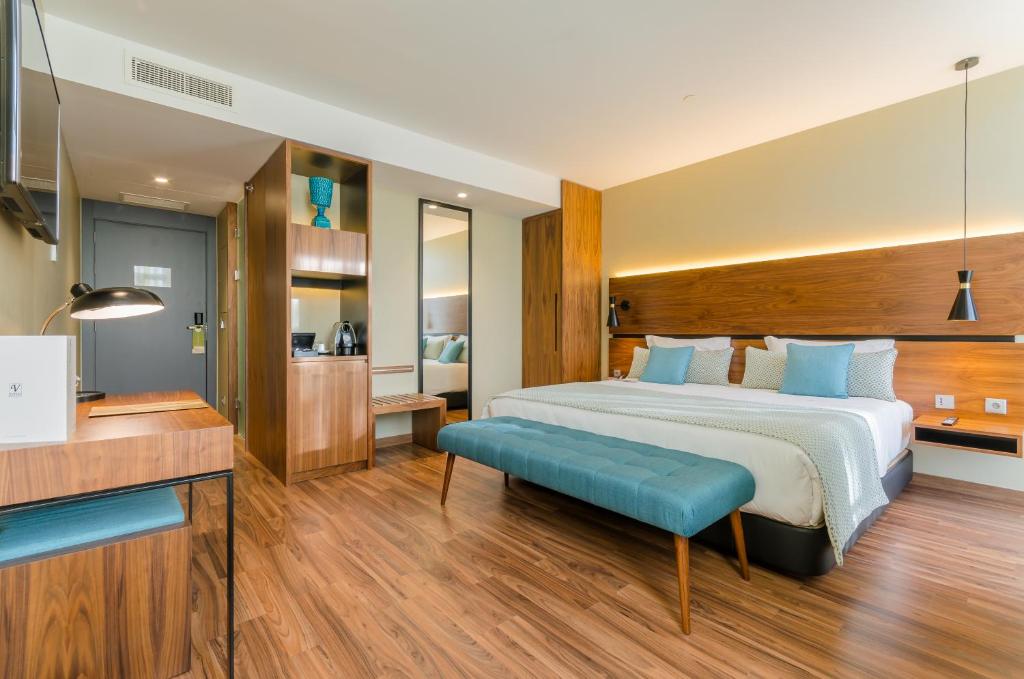 里斯本利贝尔达迪文奇酒店的一间卧室设有一张大床和一张蓝色长凳