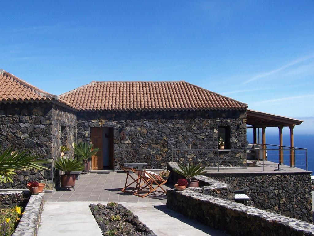 丰卡连特德拉帕尔马Casa El Mirador的一座石头房子,设有庭院,背景是大海