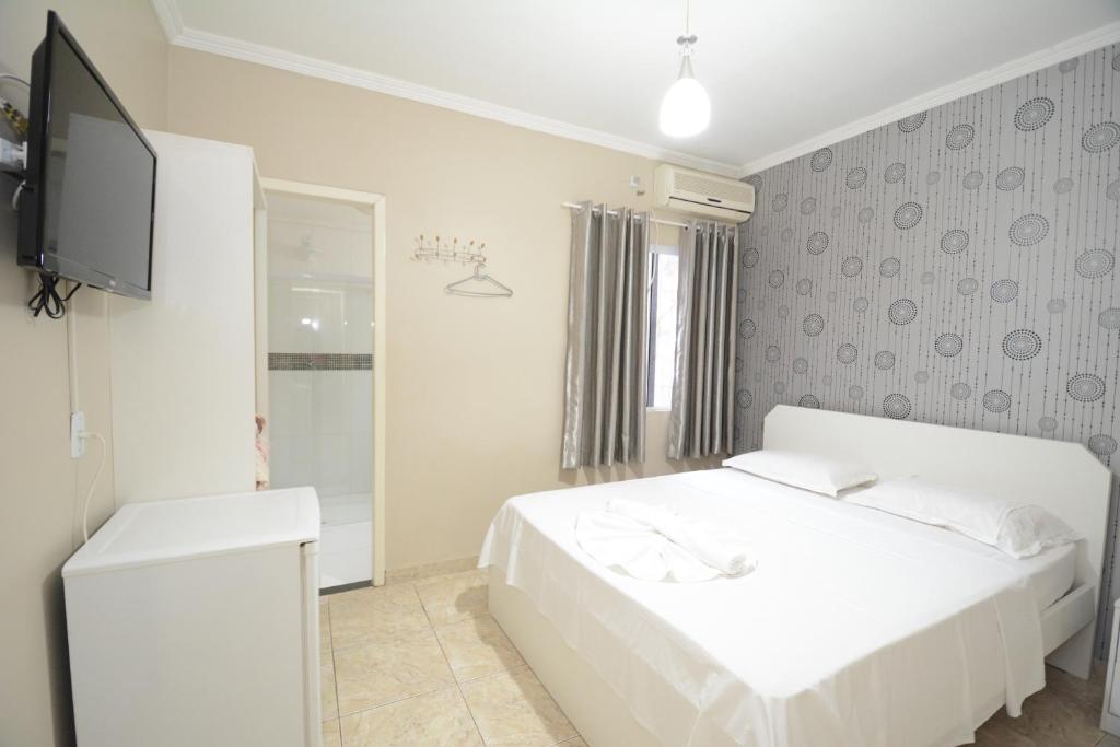 伊瓜苏科德斯道瓜旅馆的白色的卧室配有白色的床和电视。