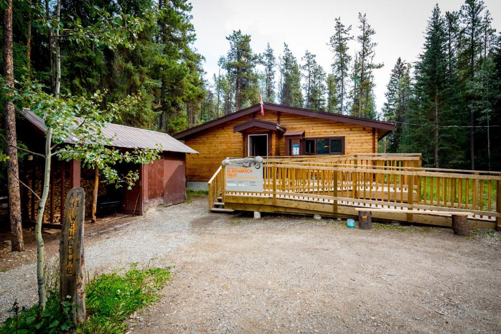 贾斯珀HI Athabasca Falls - Hostel的树林中的小屋,设有大型木甲板
