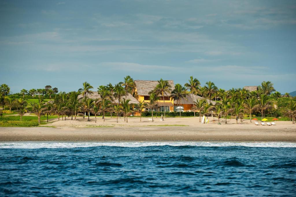 卡约港Tanusas Retreat & SPA的棕榈树和房屋的海滩和海洋