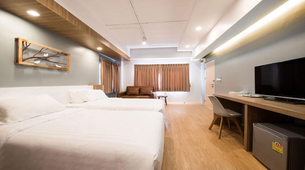 曼谷Shade House - Bitec Bangna的酒店客房设有两张床和一张书桌及电视