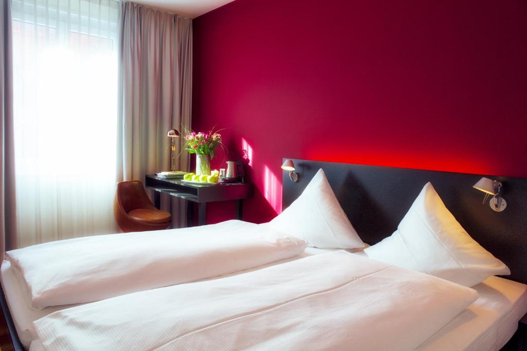 苏黎世苏黎世蒙塔那酒店的一间卧室设有两张白色的床和红色的墙壁