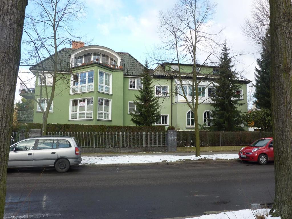 柏林富力德里沙根公寓的一座绿色房子,前面停有汽车