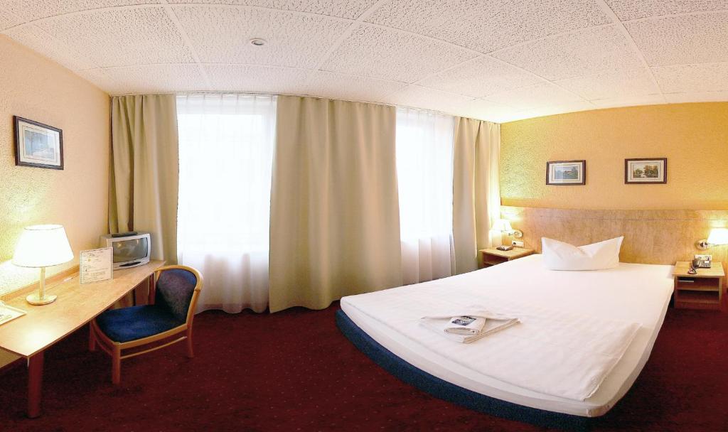 莱比锡莱比锡阿尔德酒店的酒店客房设有一张大床和一张书桌。