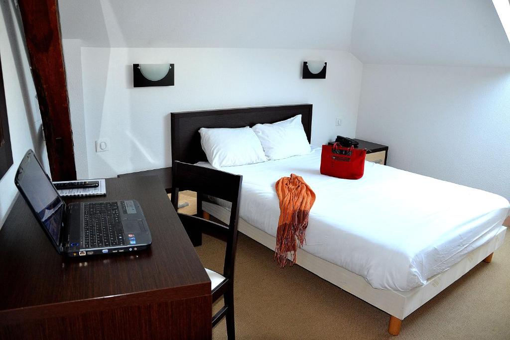 里摩日本笃会酒店的一间卧室配有一张床和一张带笔记本电脑的书桌