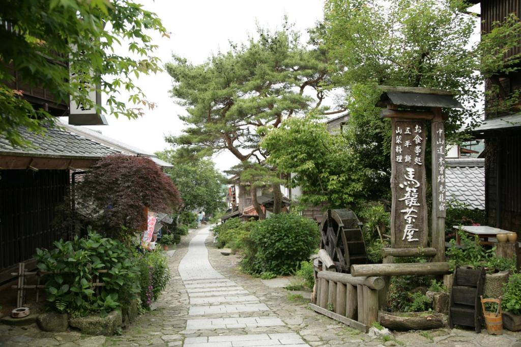 中津川市马笼茶屋的一条有标志和树木的亚洲村庄的街道