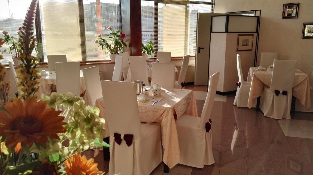 切塞纳亚历山大酒店的餐厅设有白色的桌子和白色的椅子,并鲜花盛开