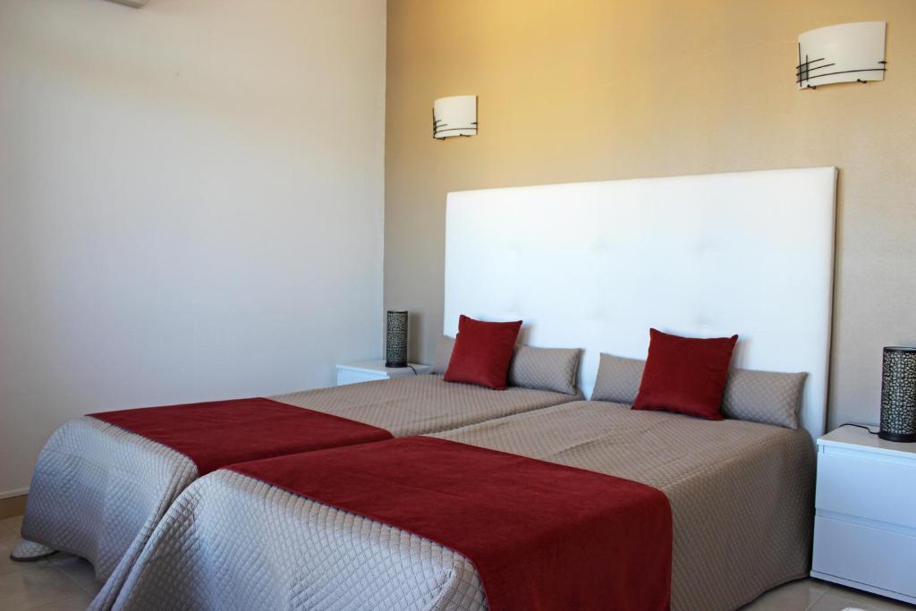 波尔蒂芒Praia da Rocha Tarik的一间卧室配有两张带红色枕头的床