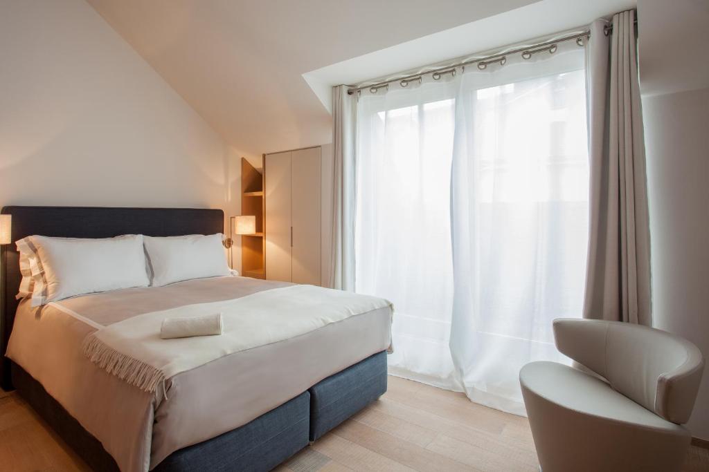 卢森堡纪尧姆套房公寓的卧室配有床、椅子和窗户。