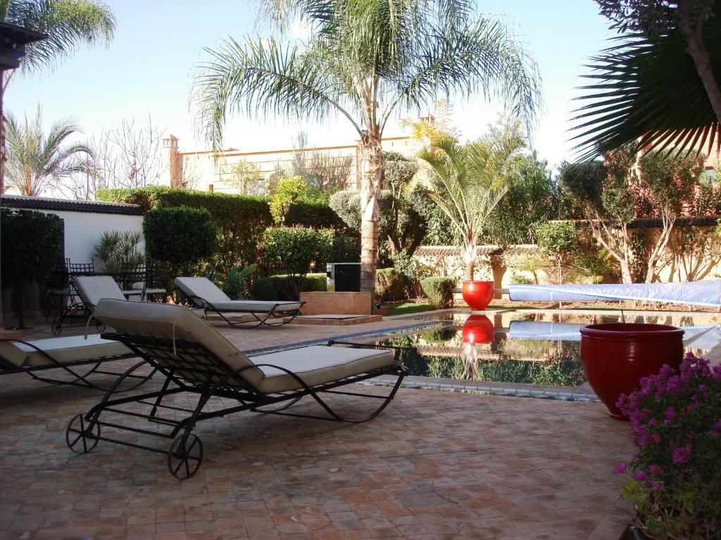 Ala el MaDar Carissa的一个带椅子的庭院和一个带喷泉的游泳池
