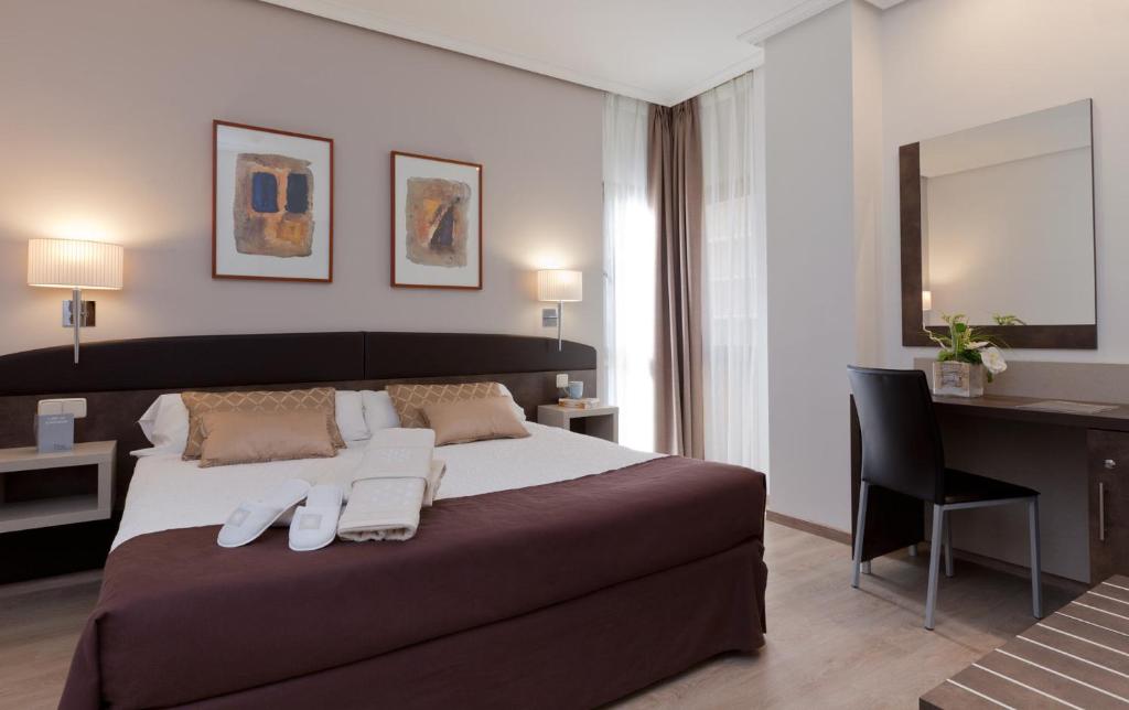 马德里马德里别墅酒店的一间卧室配有一张大床、一张桌子和一把椅子