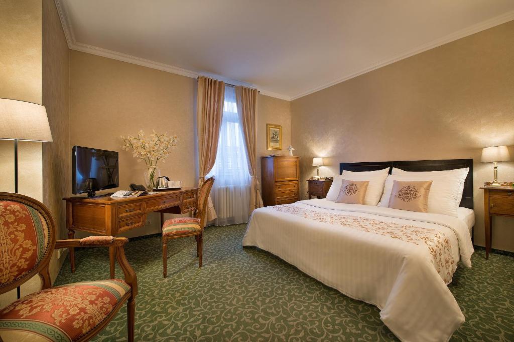 布拉格格雷斯酒店的一间卧室配有一张床、一张书桌和一台电视