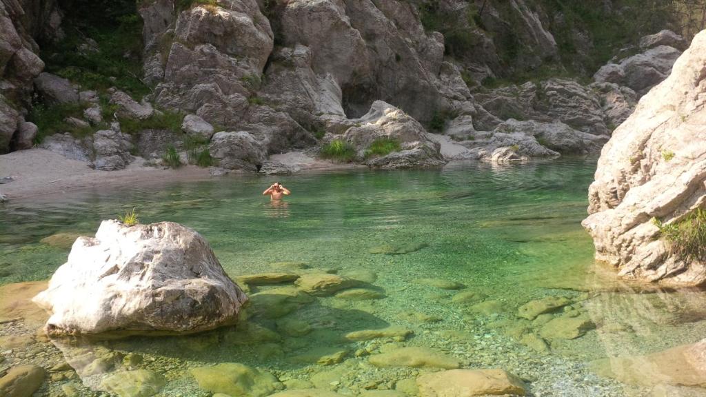 Tramonti di SopraAgriturismo Borgo Titol的水中岩石在河里游泳的人