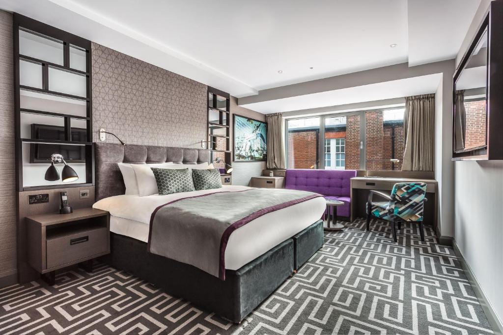 伦敦肖尔迪奇庭院酒店的酒店客房设有一张大床和一张紫色椅子