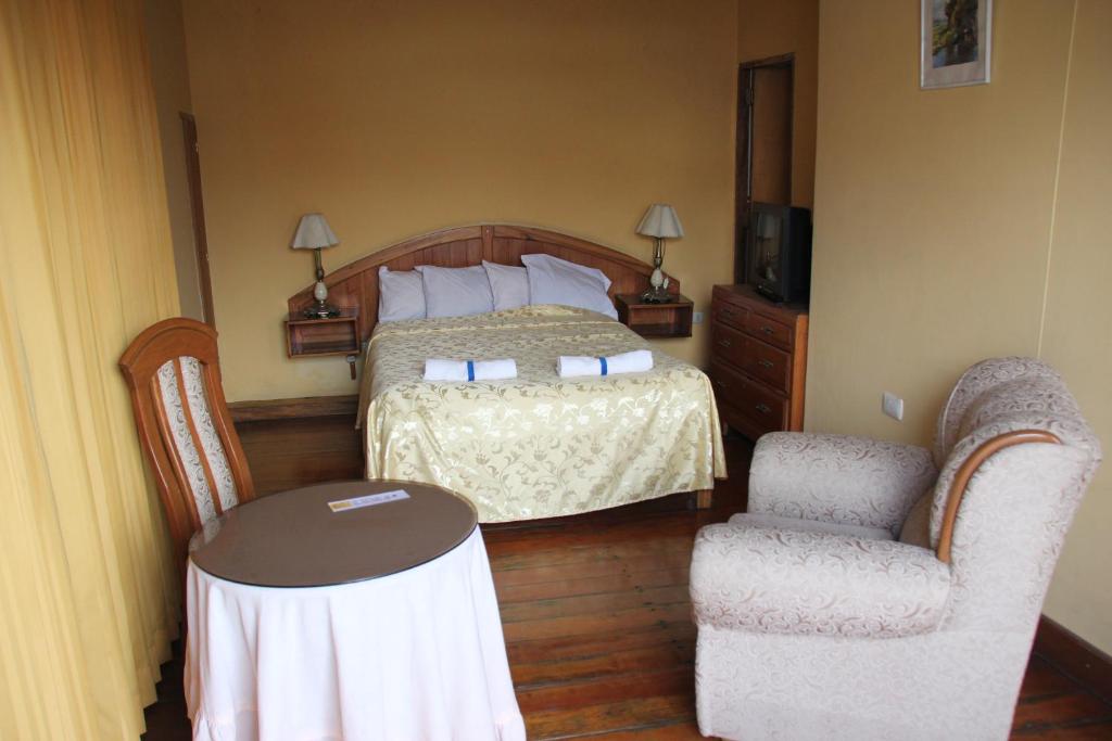 阿雷基帕Hostal Lluvia de Oro的一间卧室配有一张床、两把椅子和一张桌子