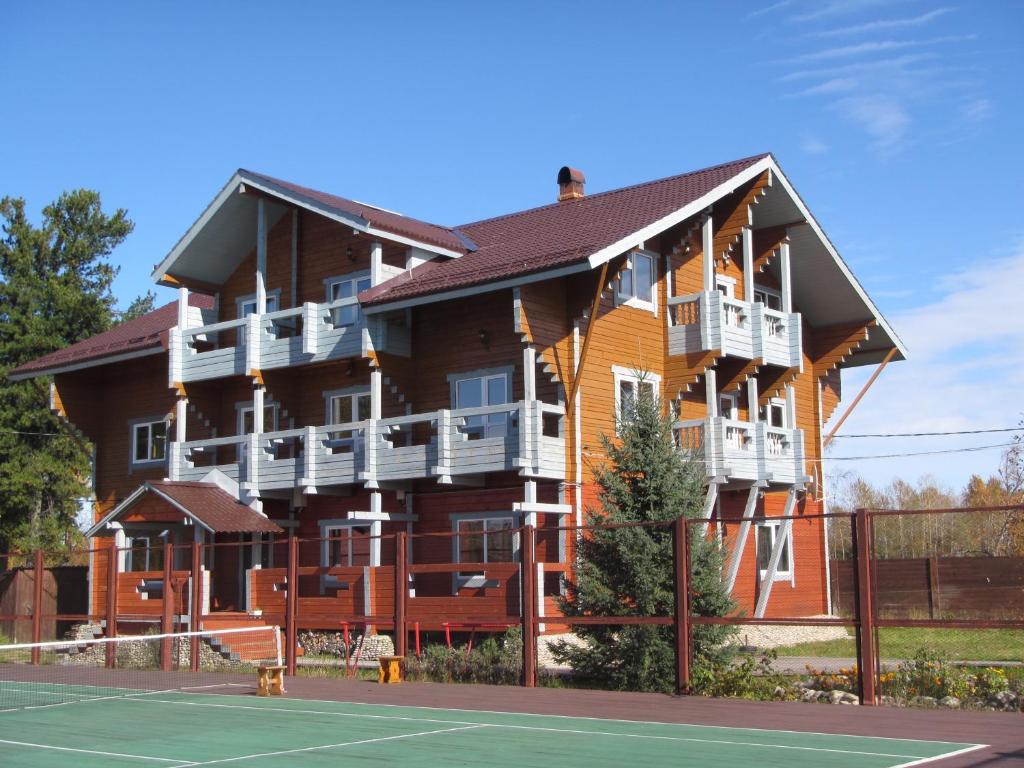 NovosnezhnayaUsadba Novosnezhka的一座大型木制建筑,前面设有一个网球场