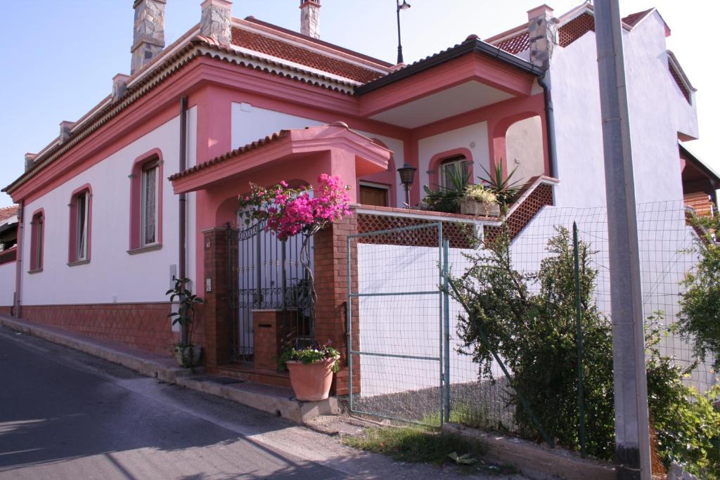 圣乔瓦尼镇La Villetta的粉红色和白色的房子,有栅栏和鲜花