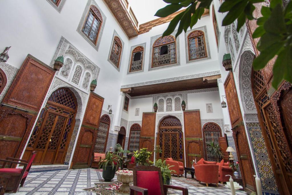 非斯Riad - Dar Al Andalous的一座清真寺的庭院,里面设有红色的椅子和木门