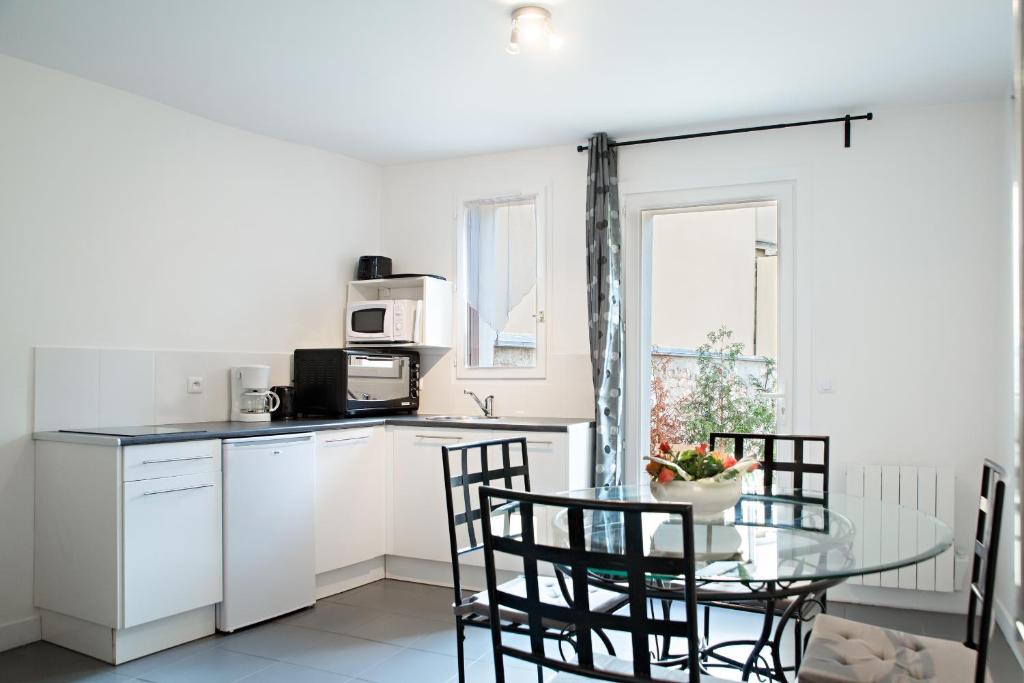 翁弗勒尔带露台公寓的白色的厨房配有玻璃桌和椅子