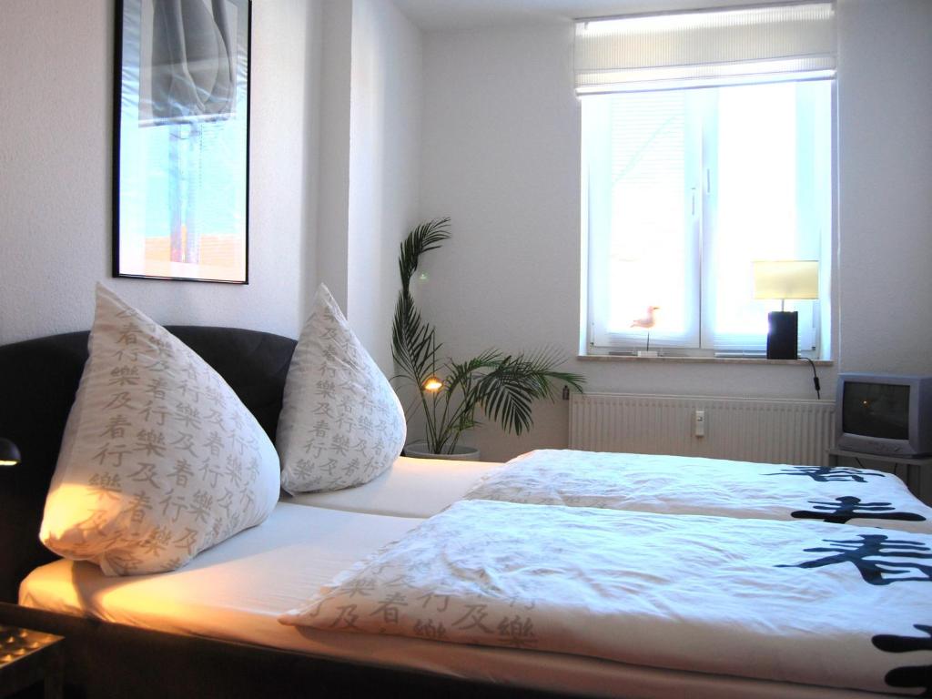 瓦尔内明德Ferienwohnung Warnemünde am Kurpark的一间卧室配有带白色床单和枕头的床。