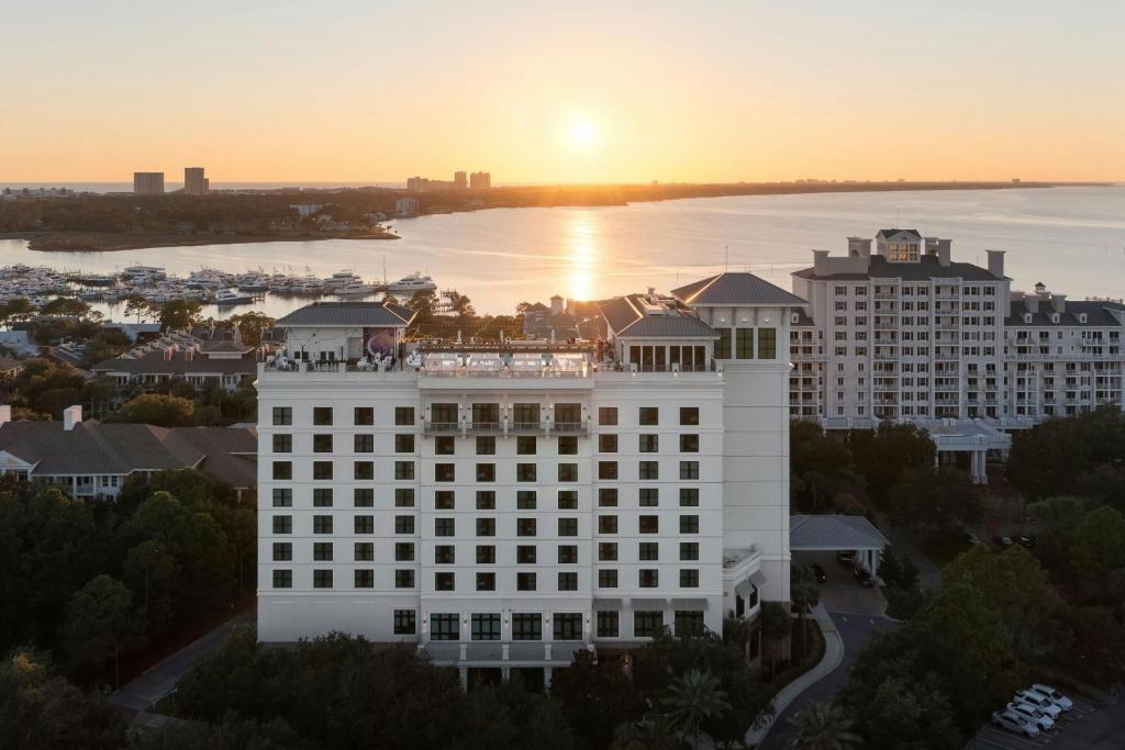 德斯坦Hotel Effie Sandestin Resort, Autograph Collection的一座白色的大建筑,背面是日落