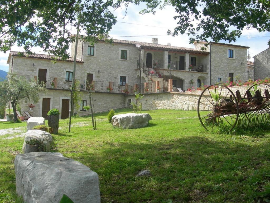 AbbateggioAgriturismo Borgo San Martino的一座石头建筑,位于一个有岩石的院子内