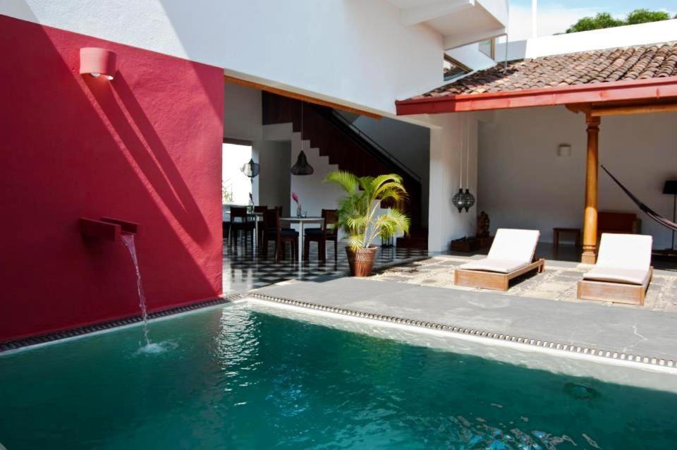 格拉纳达格拉纳达庭院酒店的一座房子,设有一座红色墙壁的游泳池