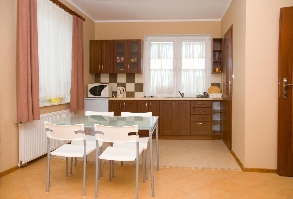 弗瓦迪斯瓦沃沃Family Homes - Sand Apartments的厨房配有玻璃桌和白色椅子