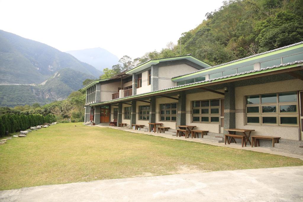 Chongde太鲁阁乐山田园民宿的一座配有桌椅的建筑,背景是群山