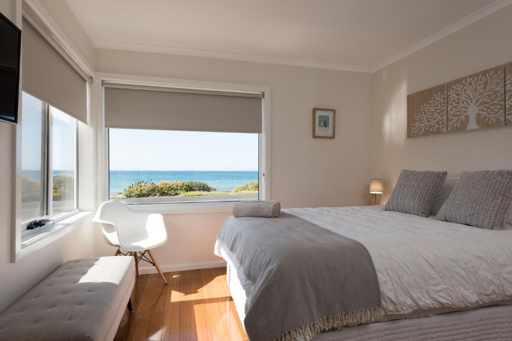 彭古因企鹅海滩度假屋的一间卧室设有一张大床和一个大窗户