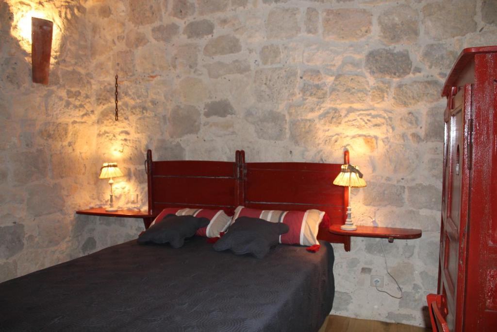 内拉克拉图尔德布拉扎勒姆住宿加早餐旅馆的一间卧室配有一张带两盏灯和石墙的床。
