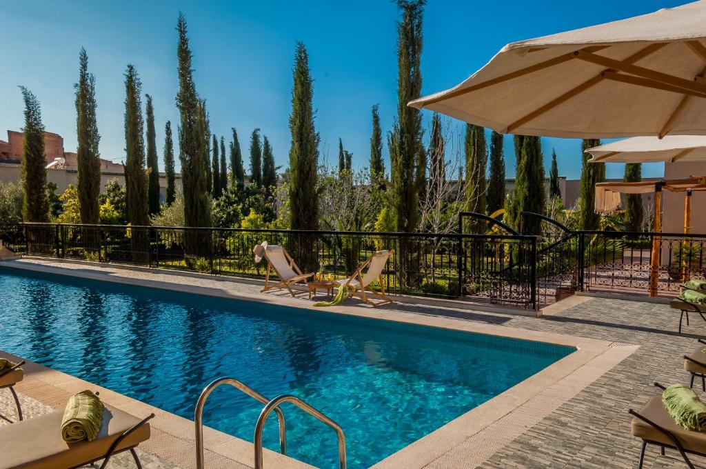 马拉喀什里亚德苏塔尼旅馆的一个带椅子和遮阳伞的游泳池