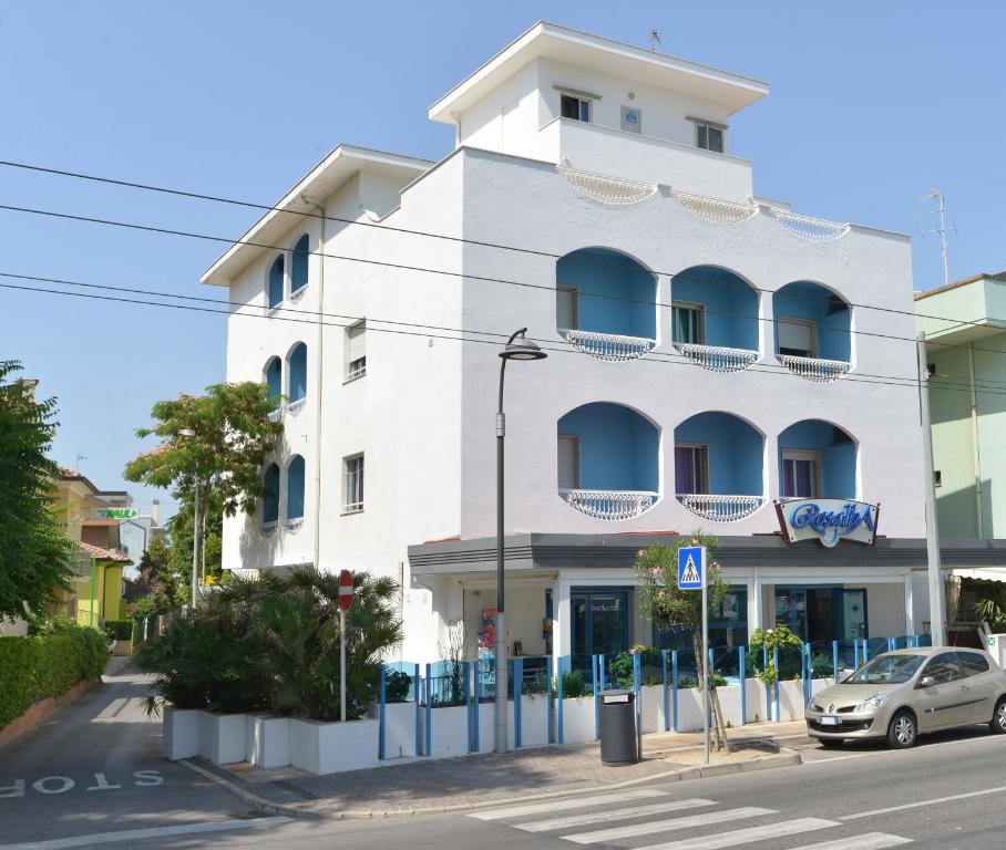 里乔内Hotel Rosalba的白色的建筑,设有蓝色的阳台,位于街道上