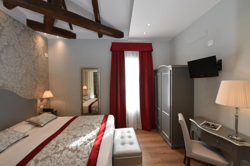 威尼斯罗莎别墅酒店的一间卧室配有一张床、一张书桌和一个窗户。