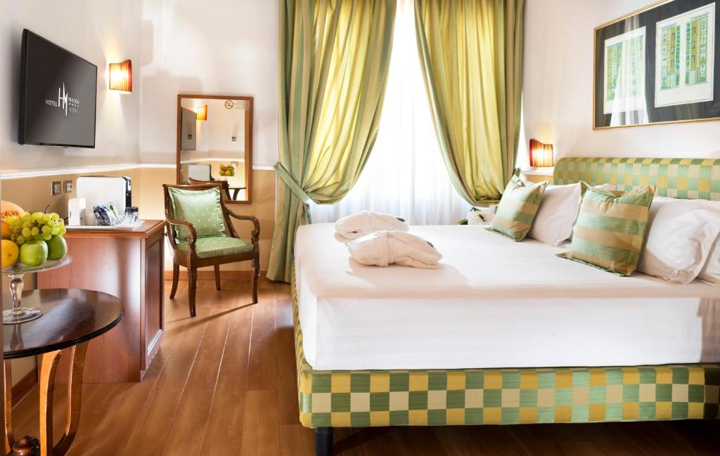 罗马罗马米尔顿酒店的酒店客房设有一张大床、一张桌子和一把椅子。