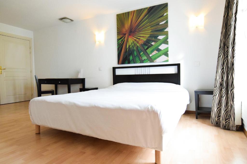 米卢斯渣油姆豪斯中央酒店的卧室配有白色的床和墙上的绘画作品