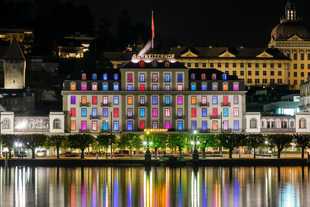 卢塞恩卢塞恩施威霍夫酒店的一座大建筑,晚上在水面上亮着五颜六色的灯光