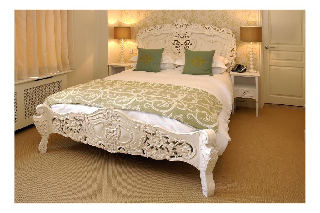谢伯恩金斯阿姆斯酒店的卧室配有带绿色枕头的白色床