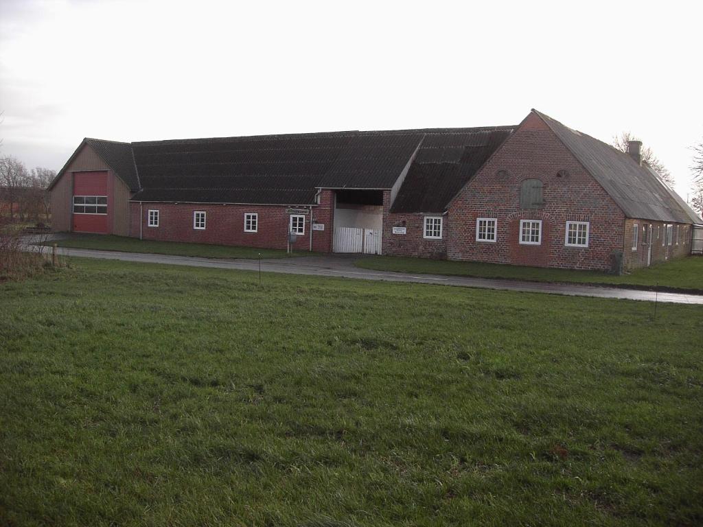 斯凯拜克Astrupgaard Farm Holiday的一座大型红砖建筑,前面有一片田野