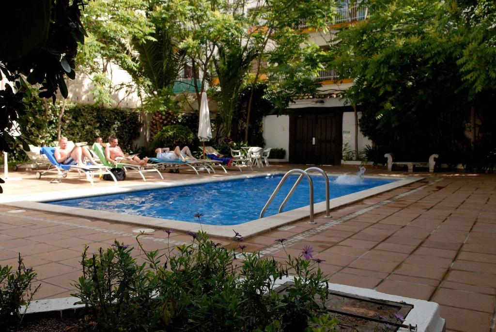 锡切斯加雷翁酒店的游泳池周围有人坐在椅子上