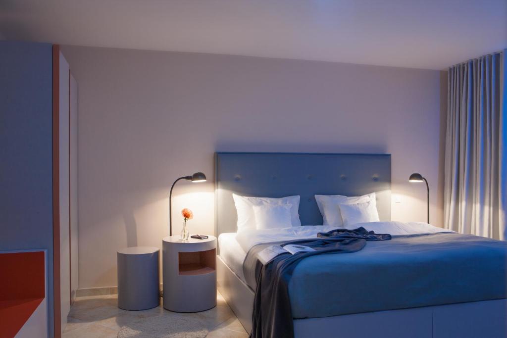 多特蒙德灰色设计酒店 的一间卧室配有一张带蓝色床罩和两盏灯的床。