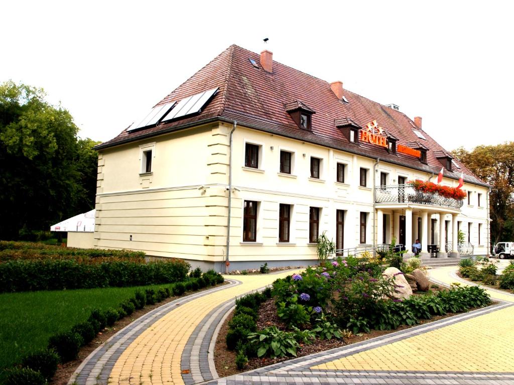 ŁobezHotel Świętoborzec的一座白色的大建筑,有红色的屋顶